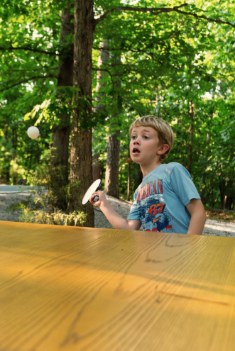 Guest playing ping pong at an outdoor table in the trees