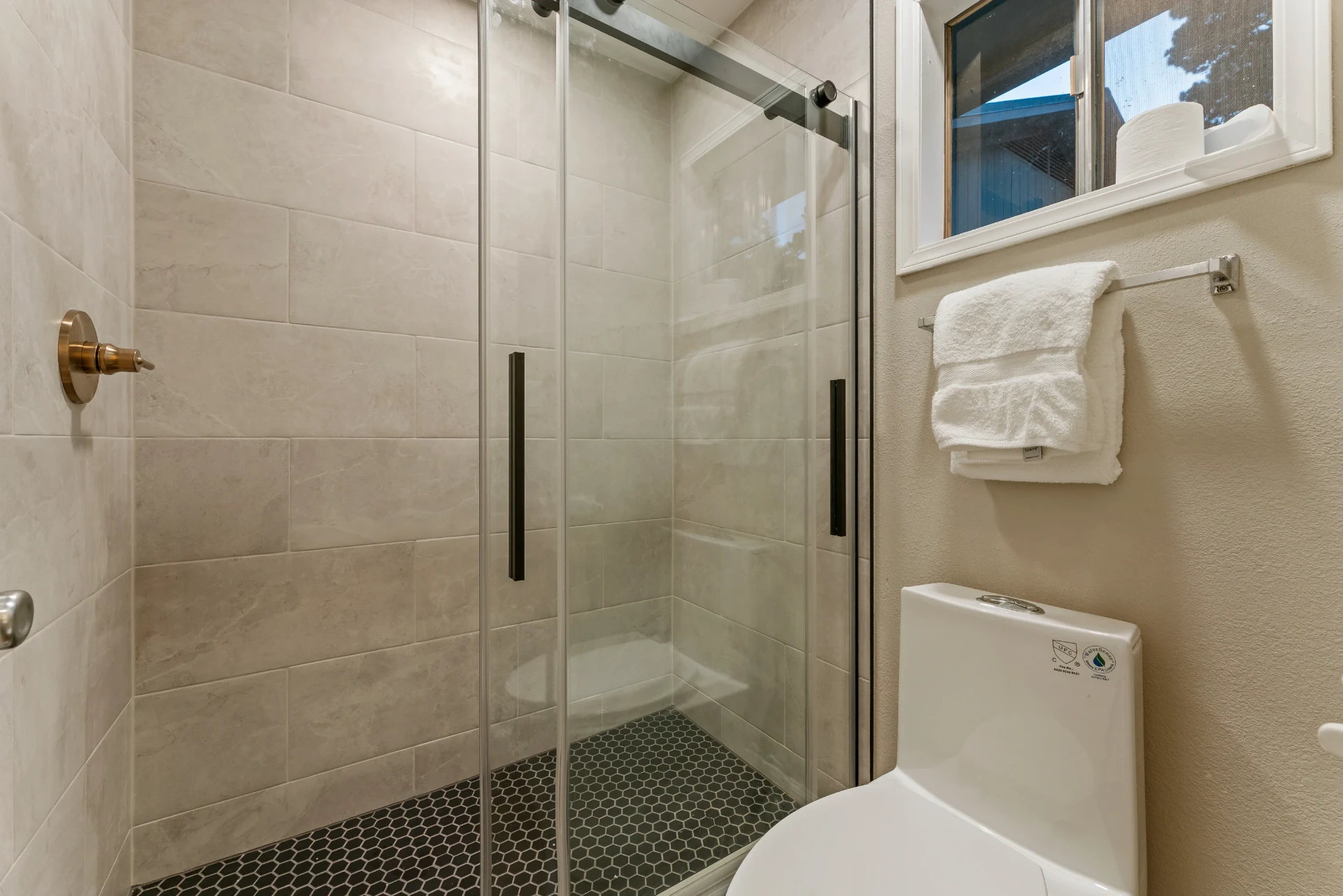 Walk-in glass shower with hexagon tile floor in the Intimate Suite