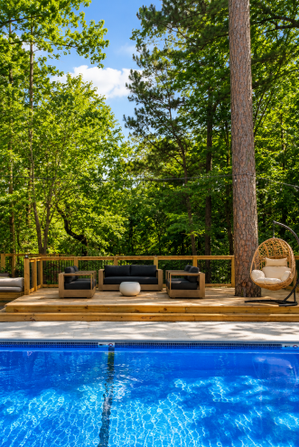 Pool deck with lounge seating surrounded by forest