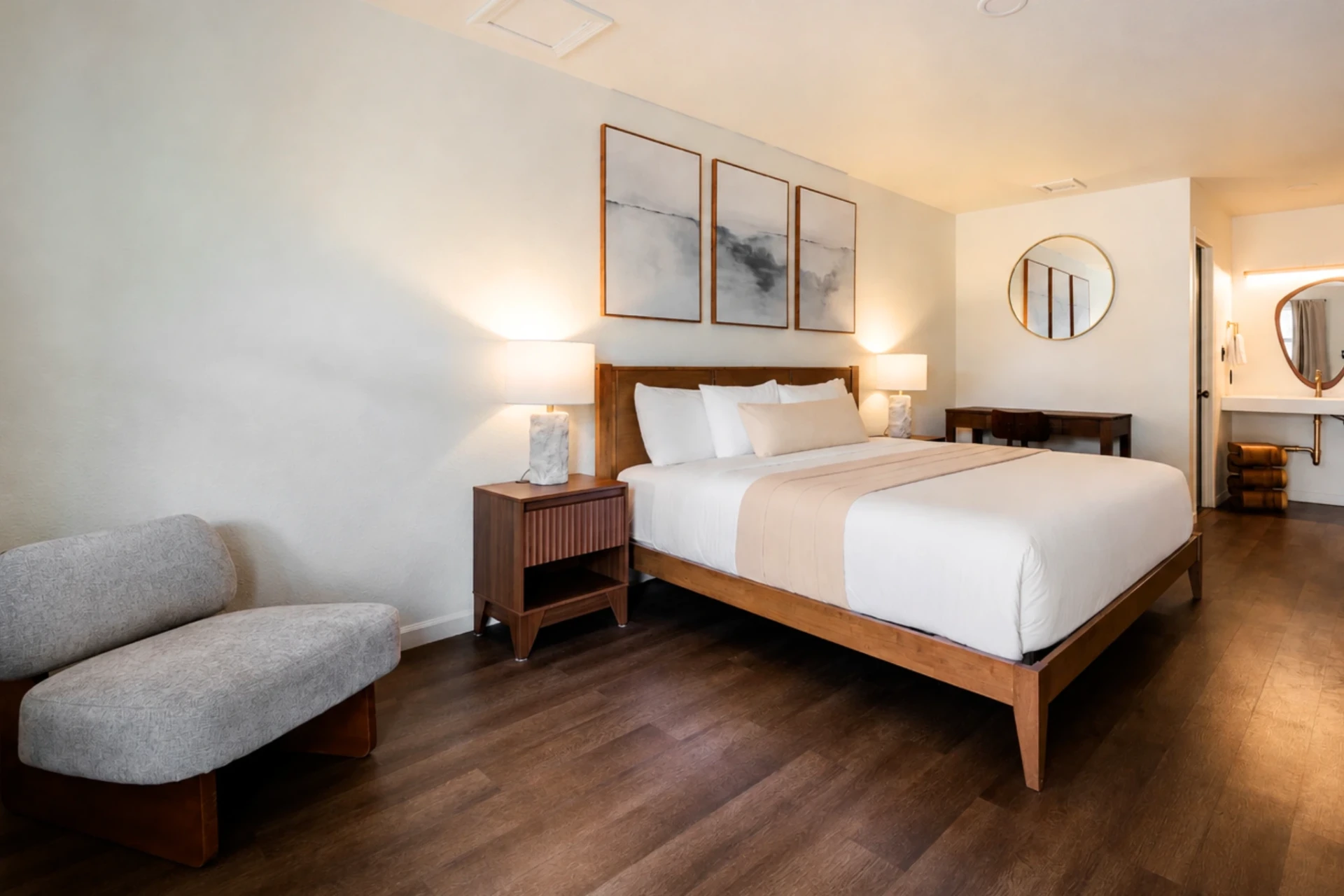 King bed with triptych artwork, warm bedside lamps, and private patio access