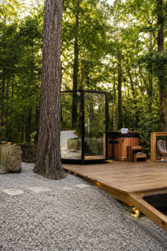 Glass-walled Nordic sauna and cedar cold plunge on a wooden deck in the Ozark forest